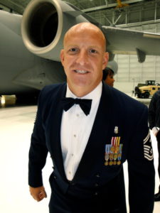 Man in tuxedo with medals of honor in front of plane