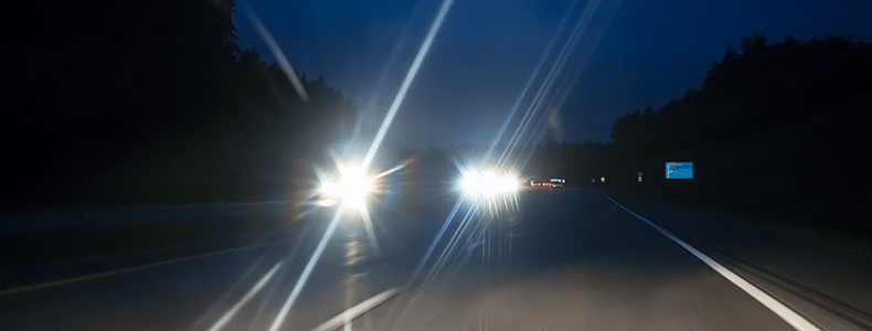 headlights with halos from oncoming vehicles on highway while night driving
