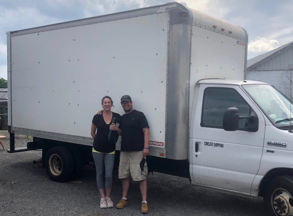 Man and woman couple standing next to white box truck