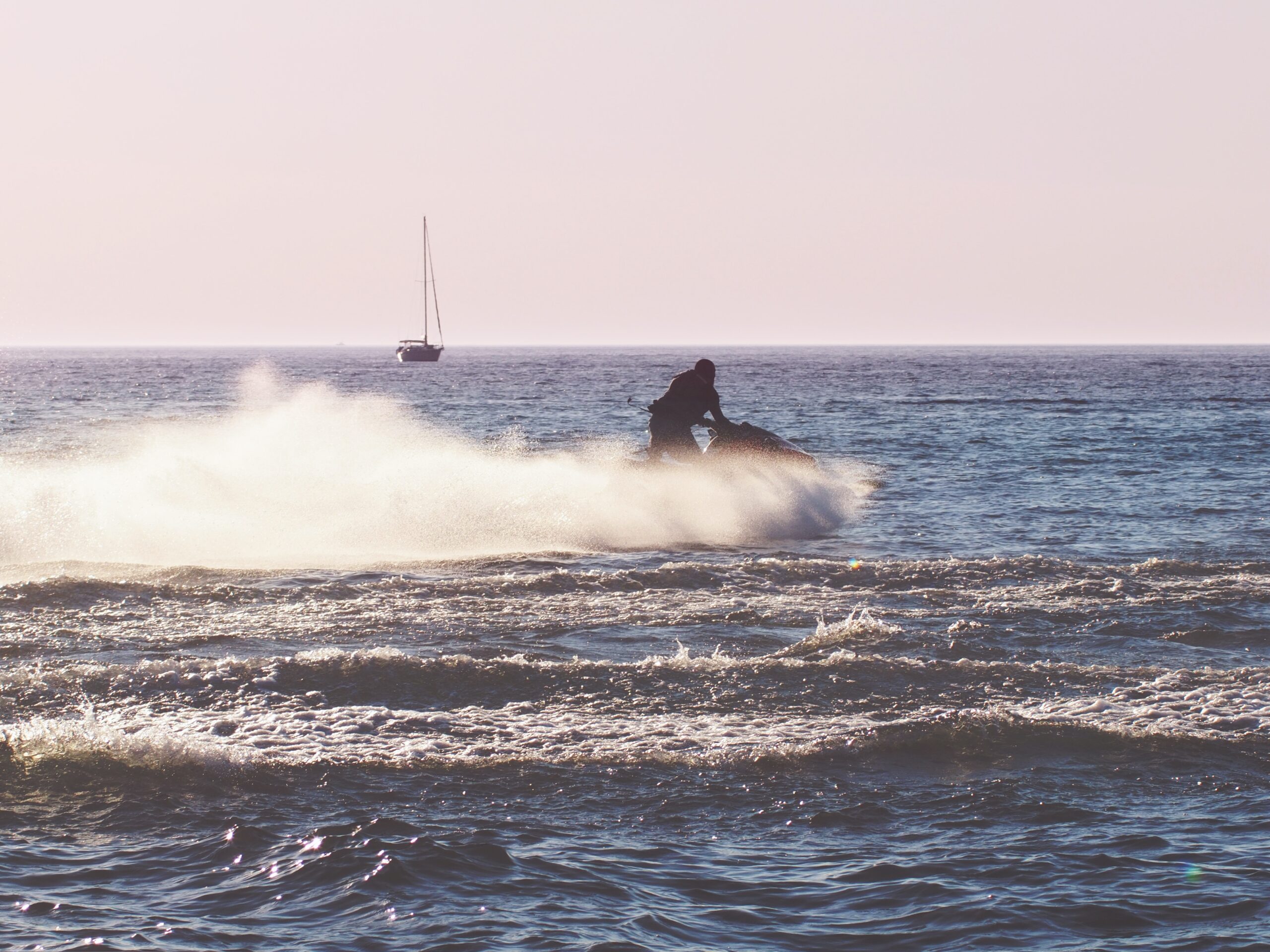 Person enjoying summertime on Lake Michigan driving a Sea-Doo with Sailboat in the background