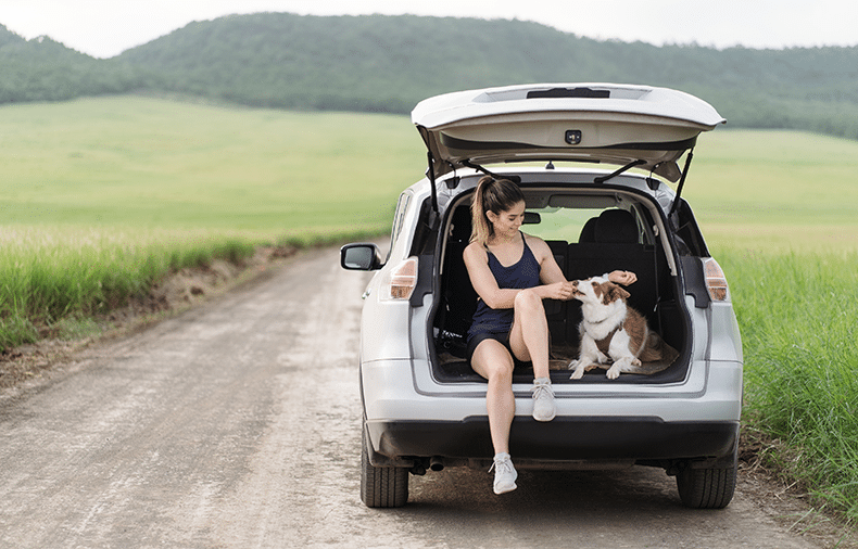 Woman sitting in back of car with her dog