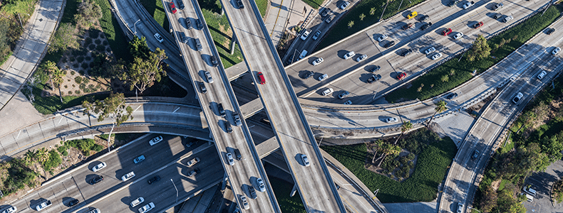 overhead image of highways with enclosed auto transport and cars