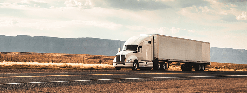 enclosed auto transport 16-wheeler traveling down open road