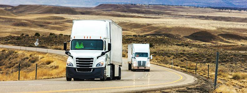 Less than load trucks traveling down winding road