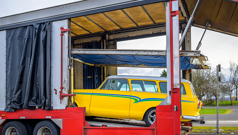 vintage yellow vehicle being loaded for enclosed transport