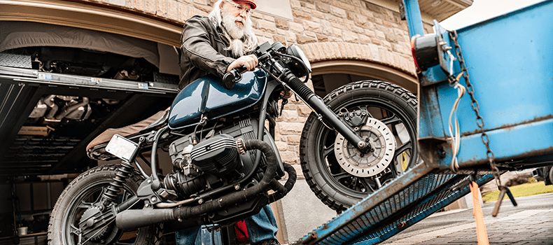 man loading bike onto trailer for motorcycle shipping
