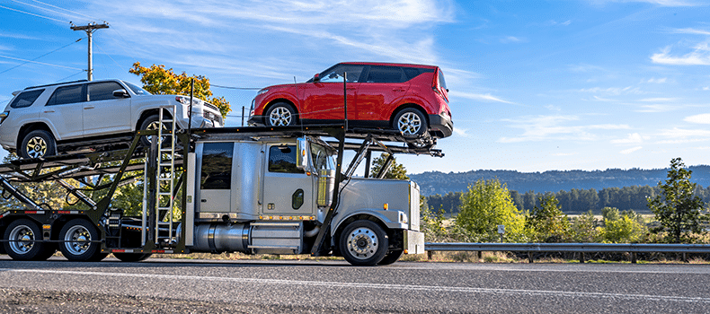 two vehicles loaded on an open trailer truck