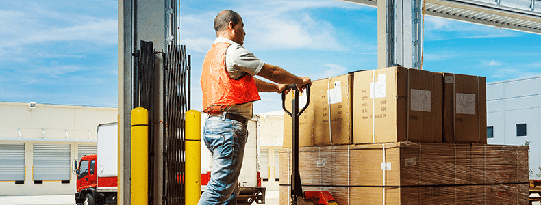worker in warehouse moving a pallet of boxes