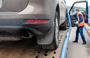 shot of a car on a flatbed truck while the carrier is in background getting ready for transport